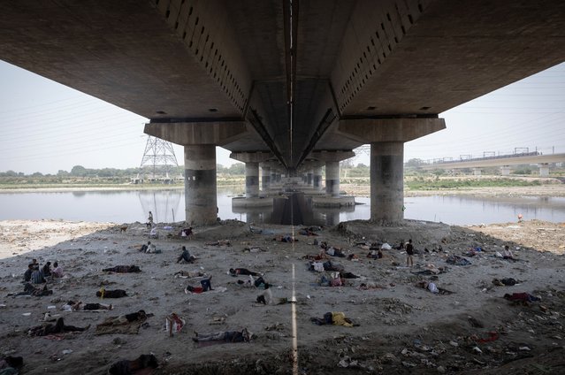People sleep on the Yamuna river bed under a bridge on a hot summer day in New Delhi, India, on May 22, 2024. (Photo by Adnan Abidi/Reuters)