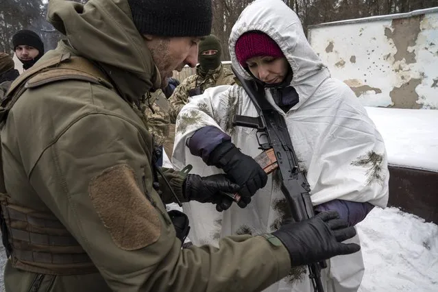 Dmytro Myhas, helps his wife Olana with her weapon during a training session on February 5, 2022 outside of Kyiv, Ukraine. (Photo by Michael Robinson Chavez/The Washington Post)