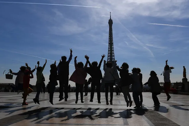 Tourists jump as they pose for a family photo on the Esplanade du Trocadero near the Eiffel Tower in Paris on March 30, 2017. (Photo by Gabriel Bouys/AFP Photo)