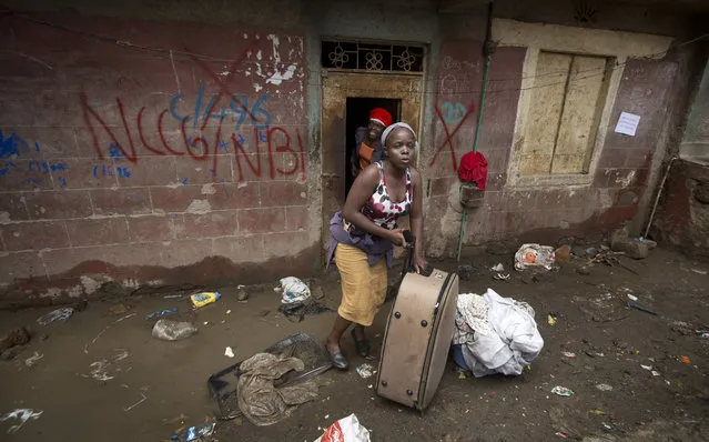 Women carry some of their belongings, as they and others are evicted from their apartment blocks close to the site of last week's building collapse, after their homes were deemed unfit for habitation and marked with a red “X” for demolition, in the Huruma neighborhood of Nairobi, Kenya Friday, May 6, 2016. (Photo by Ben Curtis/AP Photo)