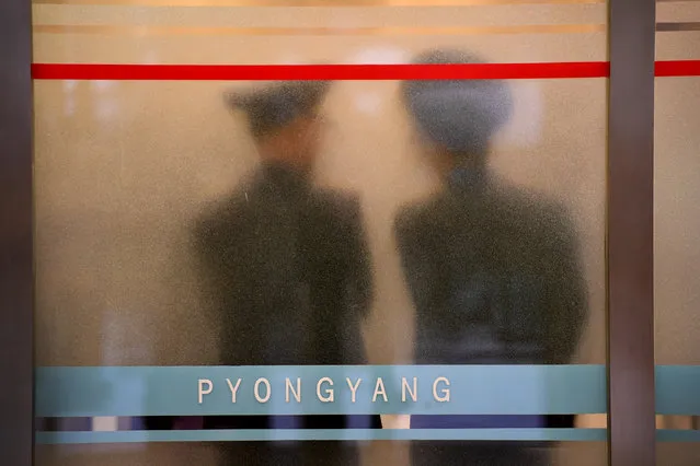Military customs officials chat behind an glass obscuring inspections at the main airport in Pyongyang, North Korea on May 3, 2016. Numerous media are descending on Pyongyang this week as the ruling Workers' Party holds it's seventh congress, a rare and potentially significant gathering. The last time the party met was in 1980. (Photo by Linda Davidson/The Washington Post)