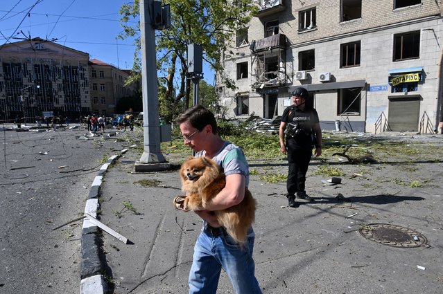 A local resident carries a dog out of a destroyed residential building following an aerial bomb in the centre of Kharkiv, on June 22, 2024, amid the Russian invasion of Ukraine. (Photo by Sergey Bobok/AFP Photo)