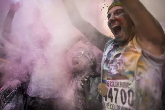 Runners frolic in a haze of colored powder in Sawyer Point Park after completing The Color Run All-Star 5K as part of the All-Star Baseball game festivities, Saturday, July 11, 2015, in Cincinnati. After more than two years of planning and sprucing up, city organizers say everything's in place for a smooth, safe and fun five days of events that began Friday morning with the opening of Major League Baseball's fan festival. (Photo by John Minchillo/AP Photo)