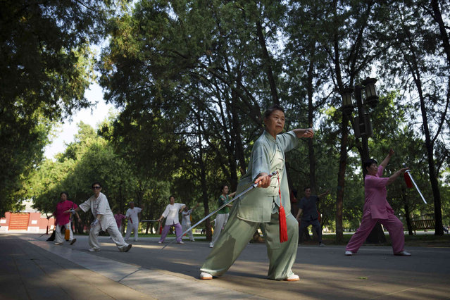 A group of Chinese practices Tai Chi with swords early morning at the Temple of Earth in Beijing, China, Friday, June 28, 2024. (Photo by Vincent Thian/AP Photo)