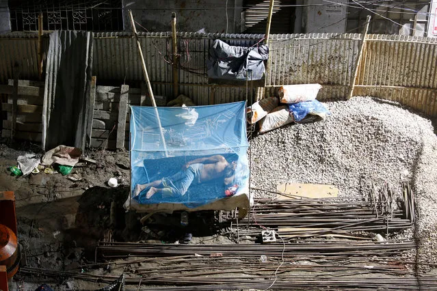 A Bangladeshi man sleep in a construction site as labors carry construction material at mid-night in Dhaka, Bangladesh, 28 June 2019. Dhaka is a one of the most populated cities in the world, built along the Buriganga river, in 2016 the population was 18 million in the greater Dhaka area. (Photo by Monirul Alam/EPA/EFE)