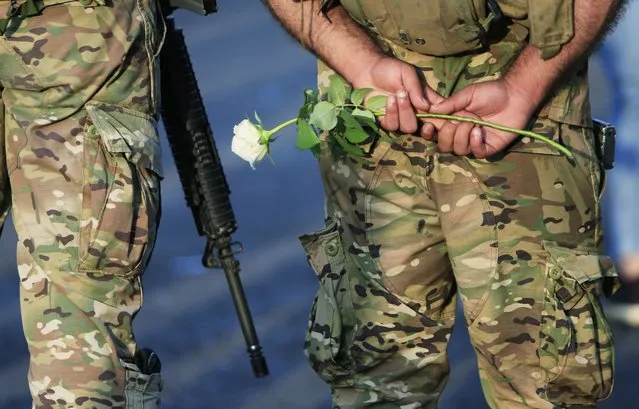 Lebanese army soldier holds a white rose as people protest over deteriorating economic situation, in the port city of Sidon, Lebanon, October 18, 2019. (Photo by Ali Hashisho/Reuters)