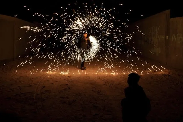 A man swings fireworks during the Muslim holy fasting month of Ramadan, in Gaza City, Saturday, April 2, 2022. (Photo by Hatem Moussa/AP Photo)