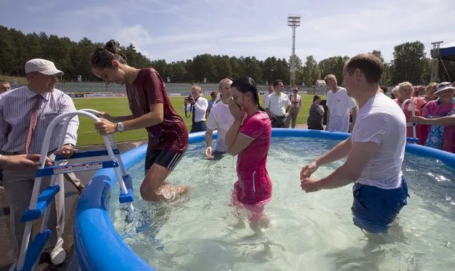 Jehovah's Witnesses are baptized in a pool during a regional congress of Jehovah's Witnesses at Traktar Stadium in Minsk, Belarus, July 25, 2015. (Photo by Vasily Fedosenko/Reuters)