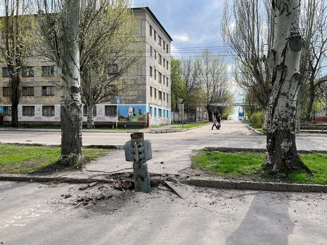 People walk along a street past a missile that stuck in the ground, amid Russia's invasion of Ukraine, in Rubizhne, Luhansk region, Ukraine, April 21, 2022. (Photo by Hamuda Hassan/Reuters)