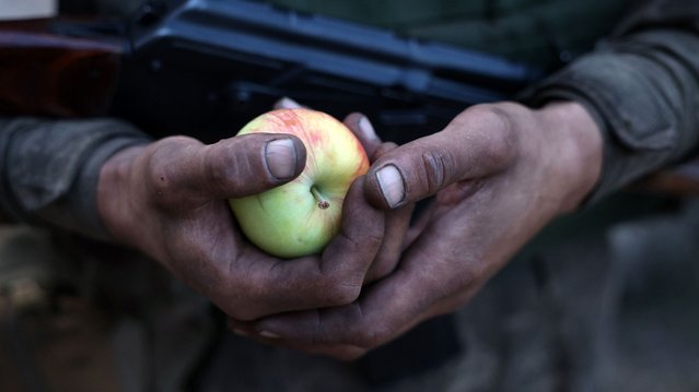 A Ukrainian infantryman of the Carpathian Sich 49th Infantry Battalion, named after Oleg Kutsyn, drafted during new mobalisation, holds an apple during a training in an unspecified location not far from front line in Donetsk region, on July 19, 2024, amid the Russian invasion in Ukraine. (Photo by Anatolii Stepanov/AFP Photo)