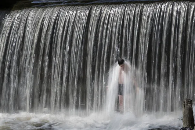 A boy cools himself off during a heat wave in Vilnius, Lithuania, Saturday, June 4, 2016. Hot weather has set in with temperatures rising up to 26 Celsius (78.8 Fahrenheit ) in Vilnius. (Photo by Mindaugas Kulbis/AP Photo)