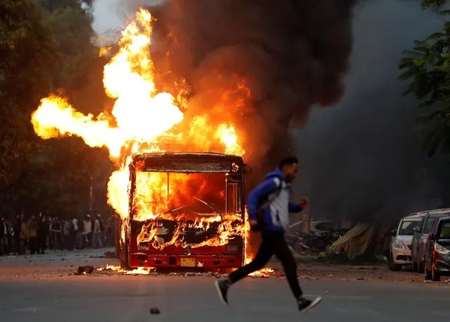 A man runs past a burning bus that was set on fire by demonstrators during a protest against a new citizenship law, in New Delhi, India, December 15, 2019. (Photo by Adnan Abidi/Reuters)