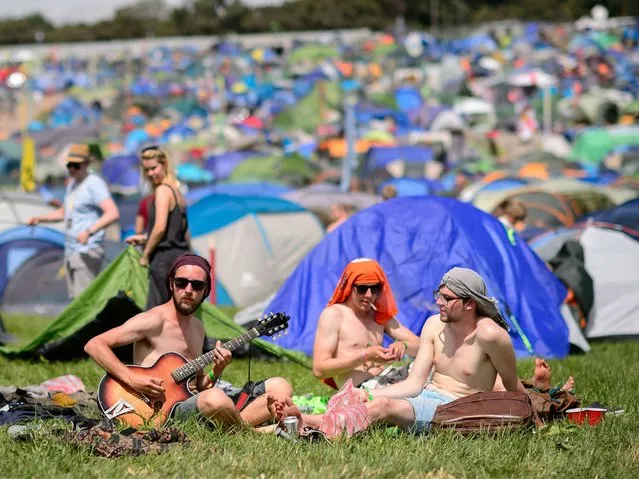 People sit in the sunshine as the Glastonbury Festival. (Photo by Leon Neal/AFP Photo)