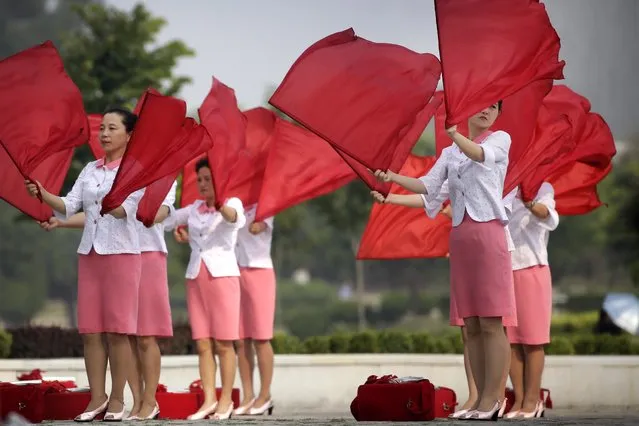 A North Korean cheerleading group wave flags to propaganda music near a road intersection as people start their day early morning on Saturday, June 17, 2017, in Pyongyang, North Korea. (Photo by Wong Maye-E/AP Photo)