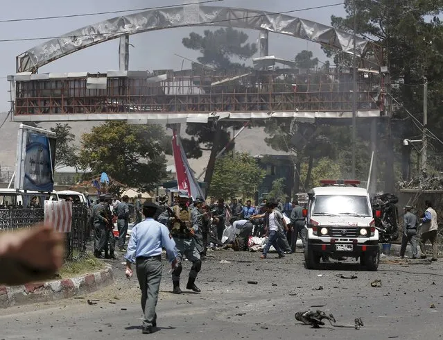 People help casualties at the site of a car bomb blast at the entrance gate to the Kabul airport in Afghanistan August 10, 2015. (Photo by Ahmad Masood/Reuters)