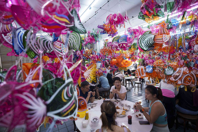 People eat under Chinese lanterns displayed at a restaurant as part of celebrations for the upcoming Mid-Autumn Festival on Penang Island, Malaysia, Wednesday, August 21, 2024. (Photo by Vincent Thian/AP Photo)