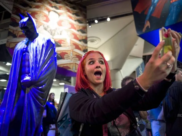Kelly O'Hara, 33, from Detroit, takes a picture of herself with a statue of Batman during the preview evening event at Comic-Con 2014 in San Diego, California, USA, 23 July 2014. (Photo by David Maung/EPA)