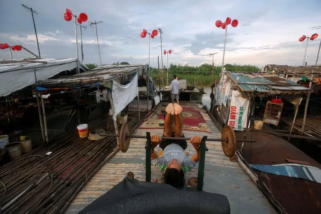 A man exercises on his boat in front of a wind power system made from plastic buckets at a floating village in Hanoi, Vietnam June 29, 2016. Picture taken on June 29, 2016. (Photo by Reuters/Kham)