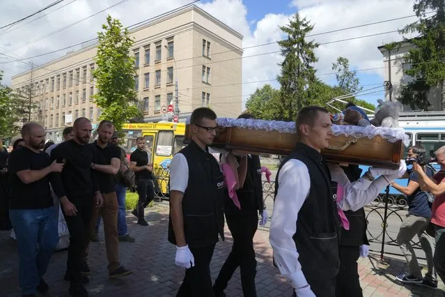 Men carry a coffin during a funeral ceremony for Liza, 4-year-old girl killed by Russian attack, in Vinnytsia, Ukraine, Sunday, July 17, 2022. Wearing a blue denim jacket with flowers, Liza was among 23 people killed, including 2 boys aged 7 and 8, in Thursday's missile strike in Vinnytsia. Her mother, Iryna Dmytrieva, was among the scores injured. (Photo by Efrem Lukatsky/AP Photo)