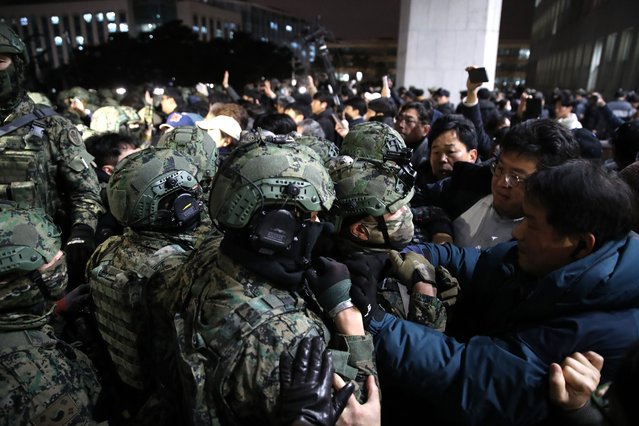 South Korean soldiers try get into the national assembly on December 04, 2024 in Seoul, South Korea. South Korean lawmakers voted to lift the declaration of emergency martial law announced earlier by President Yoon Suk Yeol in a televised speech. Since taking office two years ago, Mr Yoon has struggled to push his agendas against an opposition-controlled parliament. (Photo by Chung Sung-Jun/Getty Images)