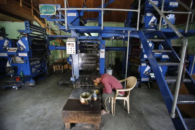Mohammad Ishaq, an employee of the Daily Kashmir Images, has his lunch near the shut down printing press machines on the outskirts of Srinagar, Indian controlled Kashmir, Monday, July 18, 2016. Authorities in India's portion of Kashmir have shut down printing presses and temporarily banned newspapers from publishing in a sweeping information blackout after days of anti-India protests left dozens of people dead in the volatile region after Indian troops killed a popular young leader of the largest rebel group fighting against Indian rule in the region. (Photo by Mukhtar Khan/AP Photo)