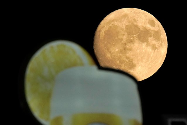 The moon rises beyond a sign in the outfield during the fifth inning of a baseball game between the Kansas City Royals and the Chicago White Sox Wednesday, Aug. 10, 2022, in Kansas City, Mo. (Photo by Charlie Riedel/AP Photo)