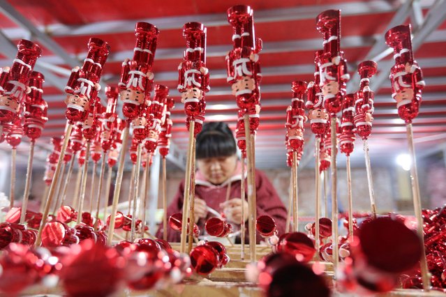 A worker makes Christmas decorations at a workshop in Huaibei, in China's eastern Anhui Province on December 10, 2024. (Photo by AFP Photo/China Stringer Network)