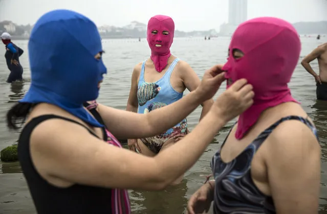 A Chinese woman adjusts another's face-kini as they swim on August 21, 2014 in the Yellow Sea in Qingdao, China. (Photo by Kevin Frayer/Getty Images)