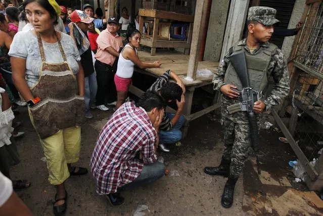 Onlookers stand by as friends mourn for a young man who was shot amidst what local media claimed are accusations of extortion from vendors at a market in Tegucigalpa August 26, 2014. Honduras and Nicaragua are among the most impoverished in the Americas, but Honduras is also blighted with the world's highest murder rate, at 90.4 homicides per 100,000 people, according to the United Nations, while Nicaragua's rate is just 11.3. (Photo by Jorge Cabrera/Reuters)