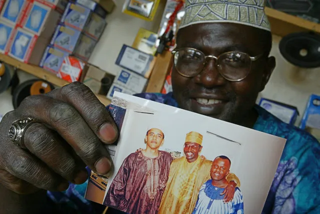 This Tuesday, September 14, 2004 file photo shows Malik Obama, the older brother of US President Barack Obama, who holds an undated picture of Barack, left, and himself, center, and an unidentified friend in his shop in Siaya, eastern Kenya. A Kenyan half-brother of President Barack Obama says he will vote for Republican presidential nominee Donald Trump and not the candidate his brother has endorsed, Hillary Clinton. Malik Obama told The Associated Press on Tuesday that he thinks Trump has a lot of energy and is very straightforward. (Photo by Karel Prinsloo/AP Photo)