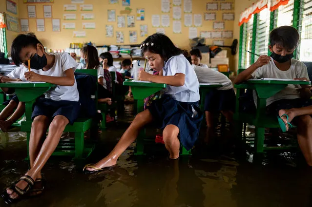 Students attend the first day of in-person classes, at a flooded school due to high tide, in Macabebe, Pampanga province, Philippines on August 22, 2022. (Photo by Lisa Marie David/Reuters)
