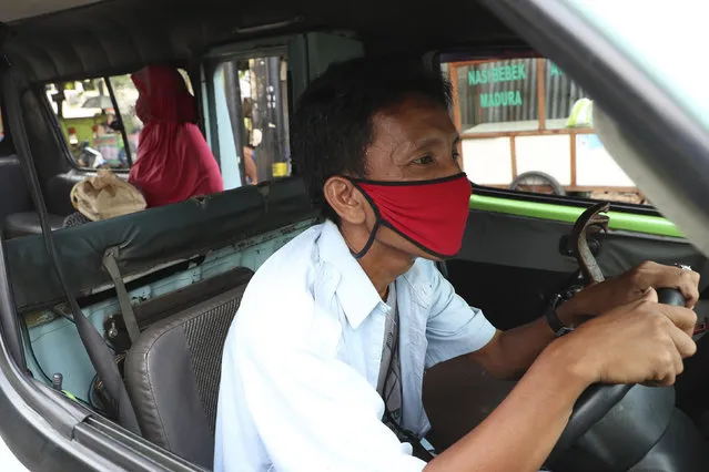 A minivan driver waits for passengers in Jakarta, Indonesia, Friday, April 10, 2020. Authorities began stricter measures to halt the new coronavirus' spread in Indonesia's capital Friday, with its normally congested streets empty after death toll spiked in the past week. (Photo by Achmad Ibrahim/AP Photo)