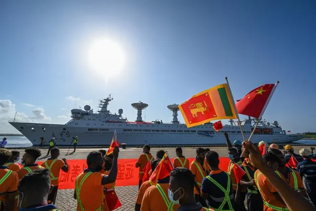 Workers wave China's and Sri Lanka's national flags upon the arrival of China's research and survey vessel, the Yuan Wang 5 at Hambantota port on August 16, 2022. A Chinese research vessel entered Sri Lanka's Chinese-run southern port of Hambantota on August 16 despite concerns from India and the US about its activities. (Photo by Ishara S. Kodikara/AFP Photo)