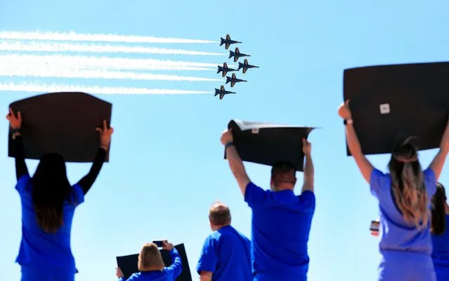 Hospital staff, including nurses, doctors, and administrators, cheer and look on as the United States Navy Blue Angels pass over Medical City Dallas on May 06, 2020 in Dallas, Texas. The flyover across the Dallas-Fort Worth area was conducted as a show of support for health care workers and first responders fighting the coronavirus (COVID-19) pandemic. (Photo by Tom Pennington/Getty Images)