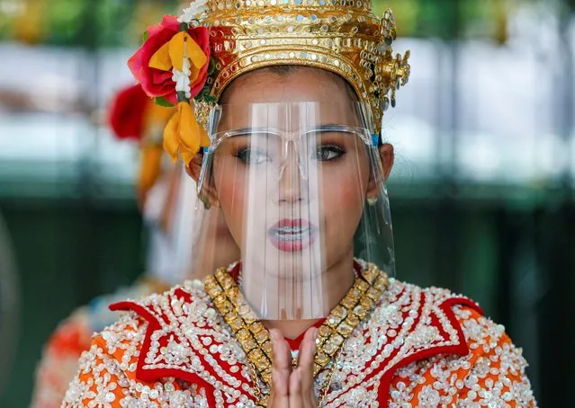 An artist wearing a protective face shield performs at the Erawan Shrine, after the government started opening some restaurants outside shopping malls, parks and barbershops during the coronavirus disease (COVID-19) outbreak in Bangkok, Thailand, May 4, 2020. (Photo by Soe Zeya Tun/Reuters)