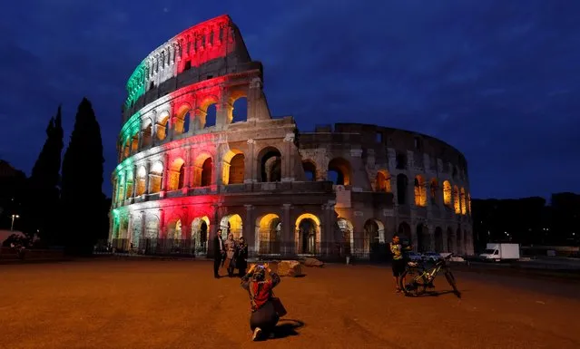 People pose for a picture in front of Rome's ancient Colosseum illuminated with colours of the Italian flag to show unity, solidarity and to honour victims of the coronavirus disease (COVID-19) from all over the world, in Rome, Italy, May 31, 2020. (Photo by Remo Casilli/Reuters)