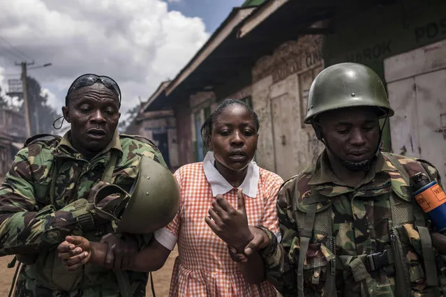 Policemen help a young schoolgirl that inhaled tear gas as the police was trying to hold off a group of supporters of opposition leader while protesting in Kawangware on October 30, 2017 in Nairobi. Kenya' s election board said it would announce today the winner of a highly contentious election, sparking fears of further violence in flashpoint opposition strongholds. (Photo by Fredrik Lerneryd/AFP Photo)