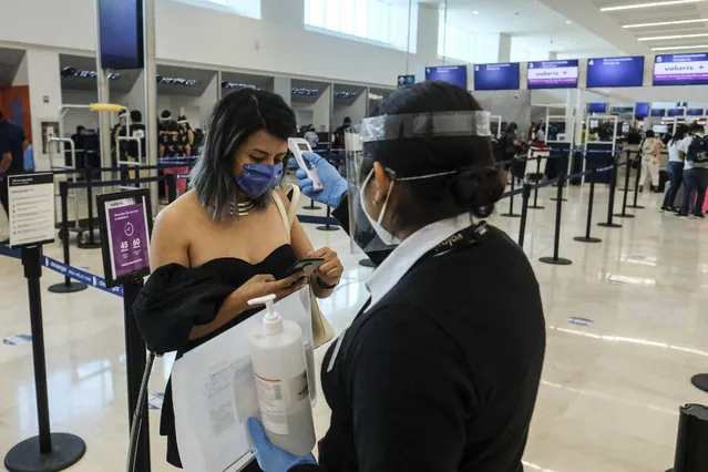Airport staff takes a passenger's temperature amid the COVID-19 pandemic in Cancun, Mexico, Saturday, June 13, 2020. In Quintana Roo state, where Cancun is located, tourism is the only industry there is, and Cancun is the only major Mexican resort to reopen so far. (Photo by Victor Ruiz/AP Photo)