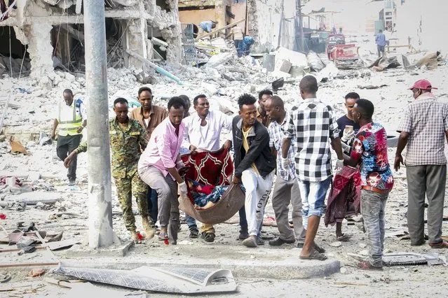 Rescuers remove a seriously-injured body from the scene of a double car-bomb attack in the capital Mogadishu, Somalia Saturday, October 29, 2022. (Photo by Farah Abdi Warsameh/AP Photo)