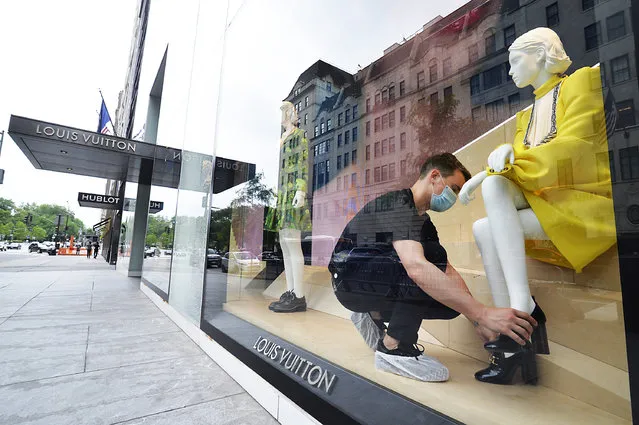 A Louis Vuitton store employee straightens up the window display as they reopen to curb side shopping only, on the corner of 5th Ave and 57th St., NYC on June 11, 2020. (Photo by Matthew McDermott/The New York Post)