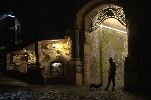 A woman walks her dog during a blackout in Kyiv, Ukraine, Friday, November 4, 2022. (Photo by Andrew Kravchenko/AP Photo)