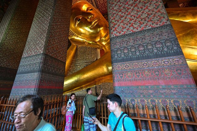Tourists take photos next to the reclining Buddha statue at the Wat Pho Buddhist temple in Bangkok on April 1, 2025, as Thai Culture Ministry officials inspected the site and it was announced a "minor" crack had been found following the March 28 earthquake. (Photo by Manan Vatsyayana/AFP Photo)