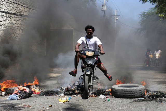A motorcyclist rides past a burning barricade during a protest against insecurity, in Port-au-Prince, Haiti, on March 19, 2025. (Photo by Jean Feguens Regala/Reuters)