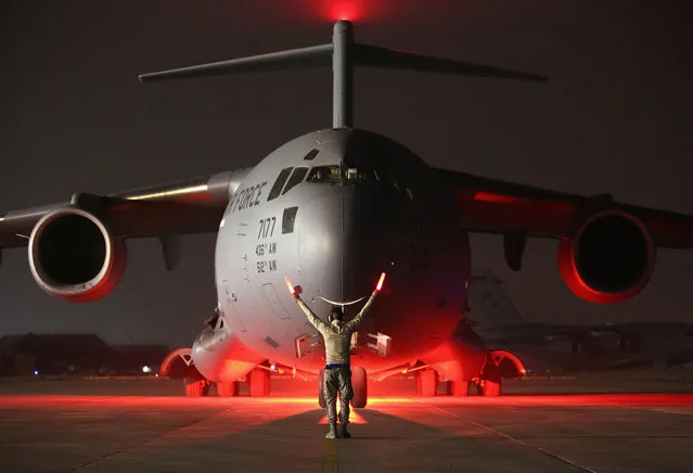 A airman guides a U.S. Air Force C-17 Globemaster after it returned from delivering cargo to Baghdad on January 9, 2016 to a base in an undisclosed location in the Persian Gulf Region. The U.S. military and coalition forces use the base to transport troops and equipment supporting Operation Inherent Resolve against the Islamic State. They also launch unmanned drones to attack ISIL positions in the region. (Photo by John Moore/Getty Images)