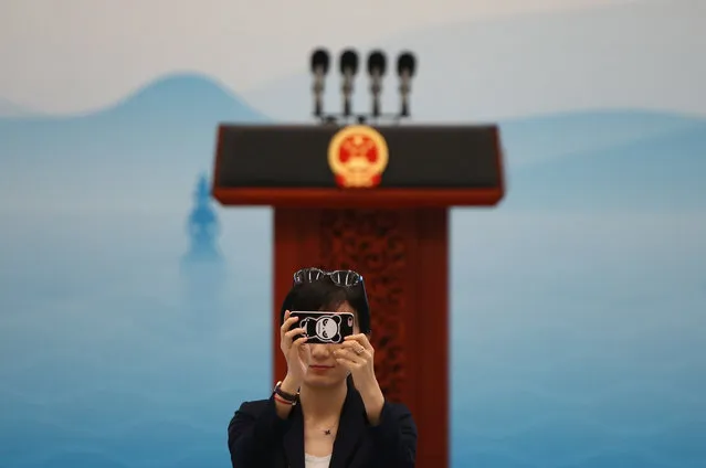 A woman takes pictures of reporters waiting for China's President Xi Jinping to attend a news conference after the closing of G20 Summit in Hangzhou, Zhejiang Province, China, September 5, 2016. (Photo by Damir Sagolj/Reuters)