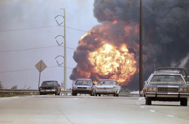 Motorists make their way along Route 95 southbound toward Philadelphia International Airport, August 10, 1987 as a fireball from a seven-alarm fire in a petroleum tank at a Chevron USA Inc. Refinery erupts behind them. (Photo by Rusty Kennedy/AP Photo)