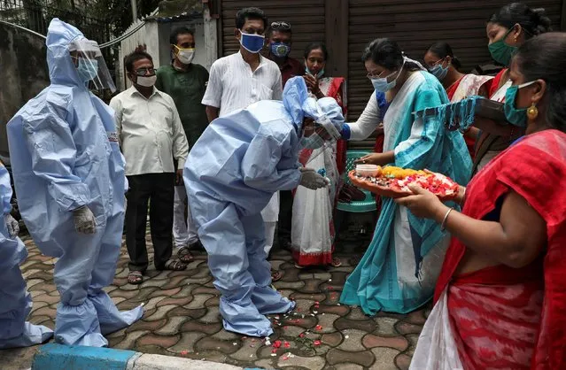 A woman ties a Rakhi, traditional Indian sacred thread, on the wrist of a municipal worker wearing personal protective equipment (PPE) to celebrate the Hindu festival of Raksha Bandha, during which a sister ties one or more of the sacred threads onto her brother's wrist to ask him for her protection, after authorities eased lockdown restrictions that were imposed to slow the spread of the coronavirus disease (COVID-19), in Kolkata, August 3, 2020. (Photo by Rupak De Chowdhuri/Reuters)