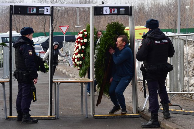 A man carrying a wreath passes through a metal detector security gate at the Borisovo cemetery ahead of the burial of late Russian opposition leader Alexei Navalny in Moscow's district of Maryino on March 1, 2024. (Photo by Olga Maltseva/AFP Photo)