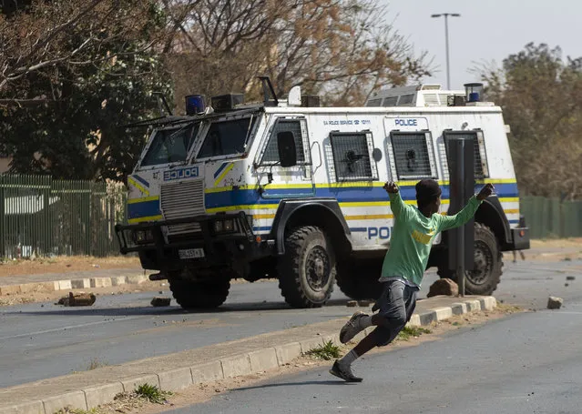 Protesters run for cover as they clash with police in Eldorado Park, Johannesburg, South Africa, Thursday, August 27, 2020. Residents from the township, south of Johannesburg are demanding justice for a teenager shot and killed, allegedly at the hands of police Wednesday. (Photo by Themba Hadebe/AP Photo)