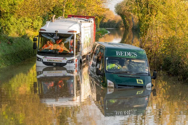 A refuge lorry wit its bin men crew remain trapped in their cab behind an abandoned school bus on November 17, 2022 as the roads flood to the highest level for years in the village of Alfriston, East Sussex, United Kingdom which burst its banks yesterday evening. (Photo by Jon Santa Cruz/The Times)